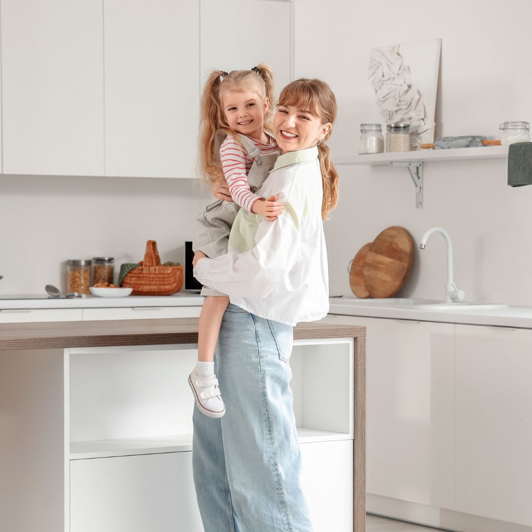 Nanny holding child in the kitchen